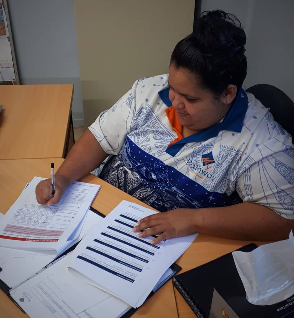 Doomadgee NDIS support worker Nalani-Rae fills out paperwork at a desk 
