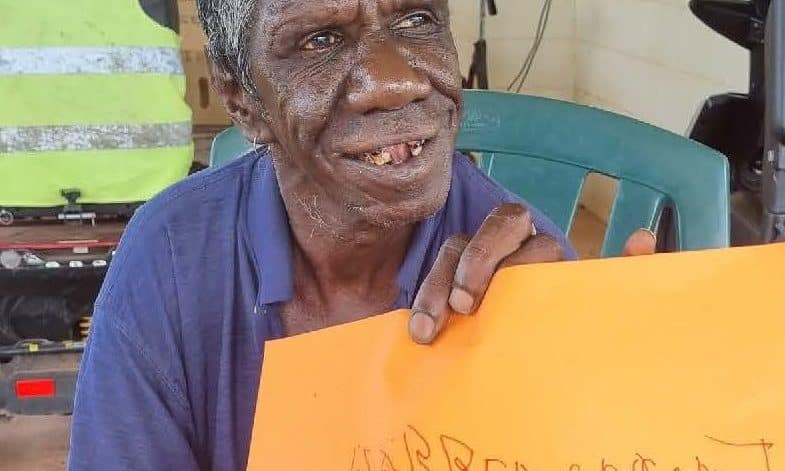 Indigenous participant Warren Coconut holds up a yellow card which he has written his name on thanks to our simple supports.